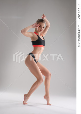 Woman poses dynamically in sport attire during a studio photoshoot session Woman poses dynamically in sport attire during a studio photoshoot session 128566308