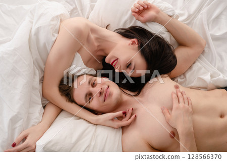 Romantic couple enjoying intimate moments in a cozy bedroom setting Romantic couple enjoying intimate moments in a cozy bedroom setting 128566370