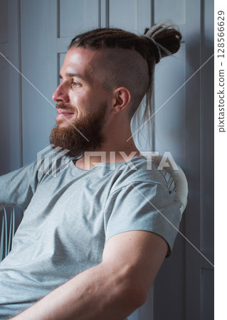 A detailed profile of a modern, trendy man who has a stylish bun and a wellgroomed beard A detailed profile of a modern, trendy man who has a stylish bun and a wellgroomed beard 128566629