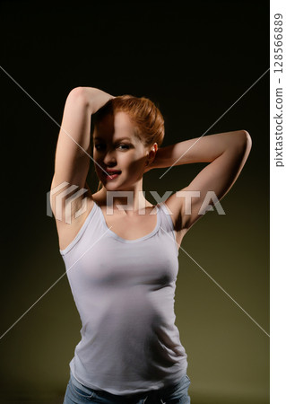 Elegant woman poses confidently in lingerie against a dark background 128566889