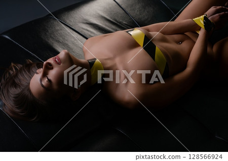 Woman reclining on a couch, showcasing beauty and elegance in a bold setting Woman reclining on a couch, showcasing beauty and elegance in a bold setting 128566924
