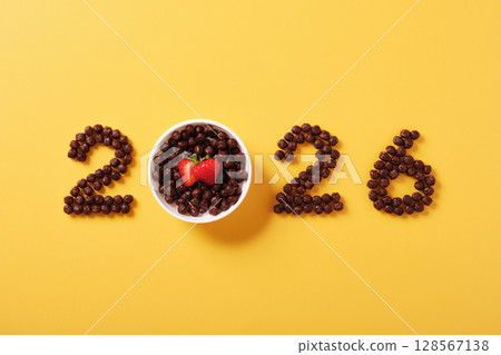 Chocolate cereal numbers form 2026 on a yellow background. Concept of new year breakfast and healthy morning start with fun food design Chocolate cereal numbers form 2026 on a yellow background. Concept of new year breakfast and healthy morning start with fun food design 128567138
