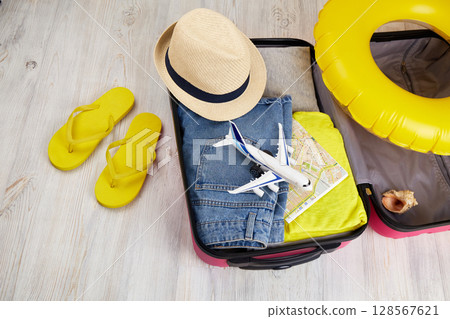 Open suitcase with clothes and leisure accessories. Summer travel Open suitcase with clothes and leisure accessories. Summer travel 128567621
