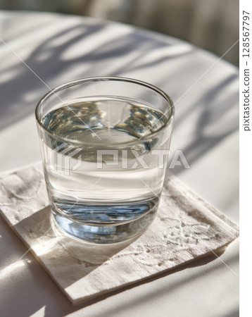 Warm Salt Water Glass Placed on a Coaster Next to an Instruction Card for Gargling During a Calm Morning 128567797