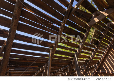 A close-up view of a rustic wooden structure showing the exposed beams A close-up view of a rustic wooden structure showing the exposed beams 128568388