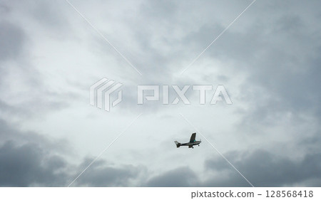 Small private plane flying in cloudy sky. White crop duster flight 128568418