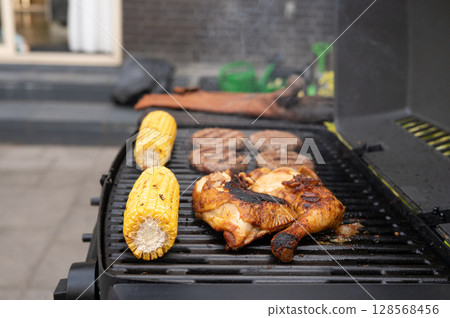Grilled chicken and corn with burgers on backyard barbecue grill Grilled chicken and corn with burgers on backyard barbecue grill 128568456