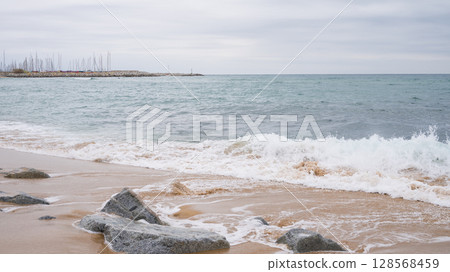 Tranquil ocean waves hitting rocky shoreline under cloudy sky Tranquil ocean waves hitting rocky shoreline under cloudy sky 128568459