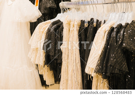 Elegant white and black sequined dresses on display in a fashion boutique 128568483