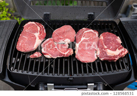 Juicy steaks grilling on outdoor barbecue for a perfect cookout experience 128568531