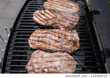Juicy steaks grilling on outdoor bbq with smoky aroma 128568534