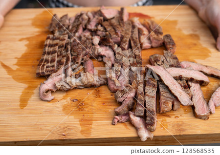 Grilled steak slices on wooden cutting board with juices visible. National Mincemeat Day 128568535