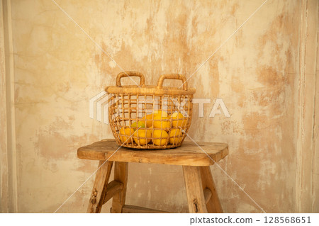 A woven basket holds fresh yellow lemons on rustic wood 128568651
