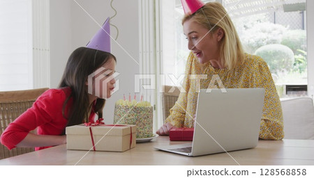 Image of balloons over happy mother and daughter with cake making birthday laptop image call 128568858
