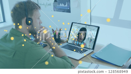 Image of bitcoin icons over caucasian man using phone headset and laptop 128568949