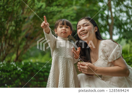 happy mother and toddler girl with Ruellia simplex or Mexican petunia flower in garden 128569424