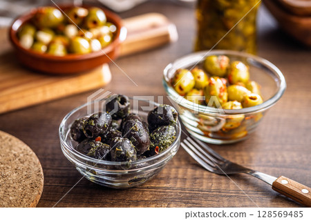 Tapas. Flavored pickled olives in bowl on wooden table. 128569485