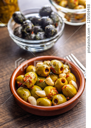 Tapas. Flavored pickled olives in bowl on wooden table. 128569488