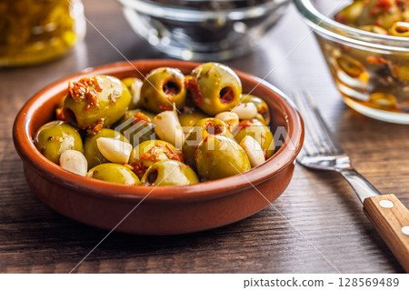 Tapas. Flavored pickled olives in bowl on wooden table. 128569489