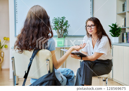 Woman school psychologist, teacher, social worker, mentor working with teenage girl Woman school psychologist, teacher, social worker, mentor working with teenage girl 128569675