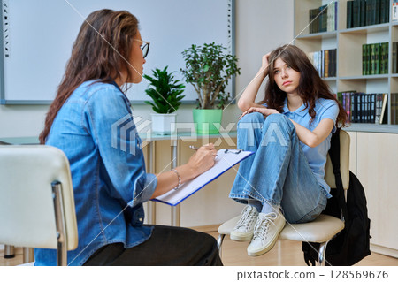 Sad teenage girl in mental therapy session, talking with school counsellor Sad teenage girl in mental therapy session, talking with school counsellor 128569676