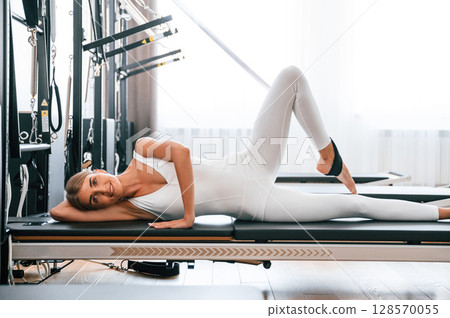 Lying down on the side. Young woman in fitness center is doing exercises Lying down on the side. Young woman in fitness center is doing exercises 128570055