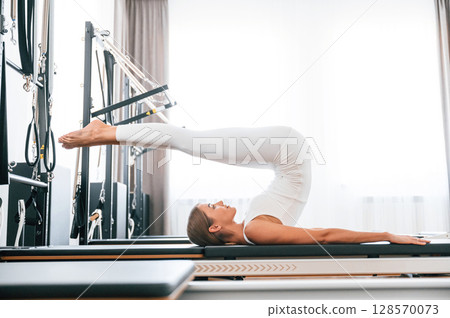 Legs are up. Young woman in fitness center is doing exercises 128570073