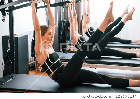 Doing abs exercises by lifting the legs. Women in fitness center Doing abs exercises by lifting the legs. Women in fitness center 128570134