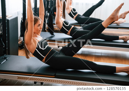 Doing abs exercises by lifting the legs. Women in fitness center 128570135