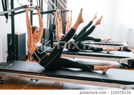 Doing abs exercises by lifting the legs. Women in fitness center Doing abs exercises by lifting the legs. Women in fitness center 128570136
