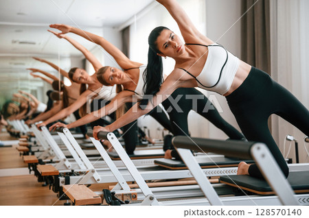 They lean to the side, do back stretches. Women in fitness center are doing exercises They lean to the side, do back stretches. Women in fitness center are doing exercises 128570140