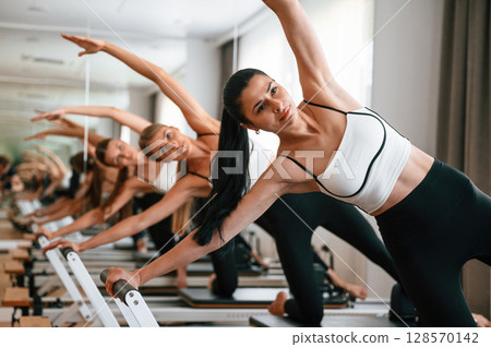They lean to the side, do back stretches. Women in fitness center are doing exercises They lean to the side, do back stretches. Women in fitness center are doing exercises 128570142