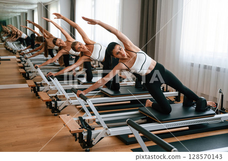 They lean to the side, do back stretches. Women in fitness center are doing exercises They lean to the side, do back stretches. Women in fitness center are doing exercises 128570143