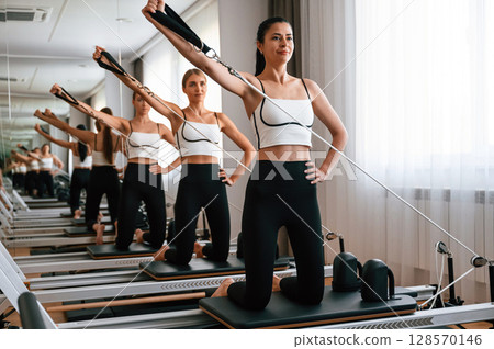 Against the mirror. Women in fitness center are doing exercises 128570146