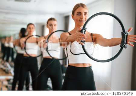 Exercises by using the circle device in hands. Women in fitness center Exercises by using the circle device in hands. Women in fitness center 128570149