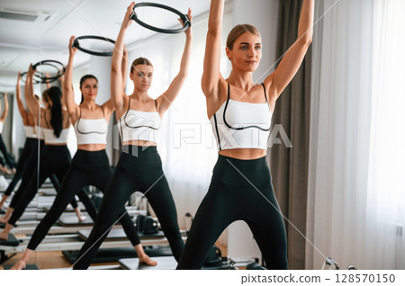 Exercises by using the circle device in hands. Women in fitness center Exercises by using the circle device in hands. Women in fitness center 128570150