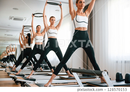 Exercises by using the circle device in hands. Women in fitness center Exercises by using the circle device in hands. Women in fitness center 128570153
