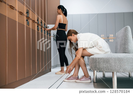 Two women is in the gym changing room with lockers 128570184