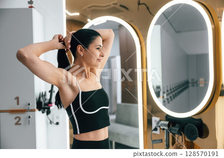 Woman is taking care of her hair in the changing room 128570191