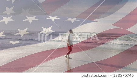 Image of flag of united states of america over senior african american man on beach 128570746