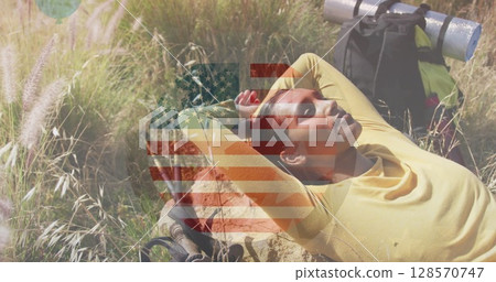 Image of american flag over biracial woman lying in mountains 128570747