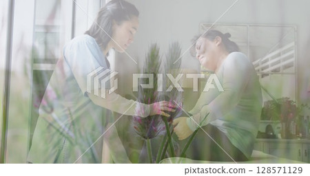Image of asian doctor treating female patient over plants 128571129