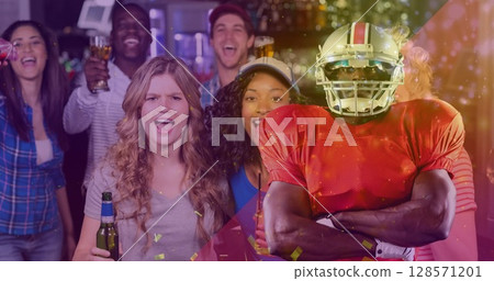 Image of confetti falling over american football player and friends celebrating with drinks 128571201