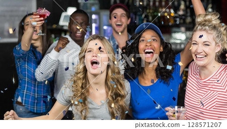 Image of confetti falling over happy diverse group of friends drinking in bar Image of confetti falling over happy diverse group of friends drinking in bar 128571207