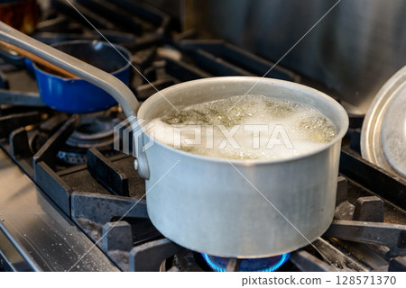 Cooking a pot on a gas stove, boiling water, restaurant kitchen 128571370