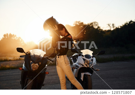 Conception of safety, wearing protective helmet. Woman is with motorcycle outdoors Conception of safety, wearing protective helmet. Woman is with motorcycle outdoors 128571807