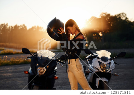 Wearing the protective helmet. Woman is with motorcycle outdoors Wearing the protective helmet. Woman is with motorcycle outdoors 128571811