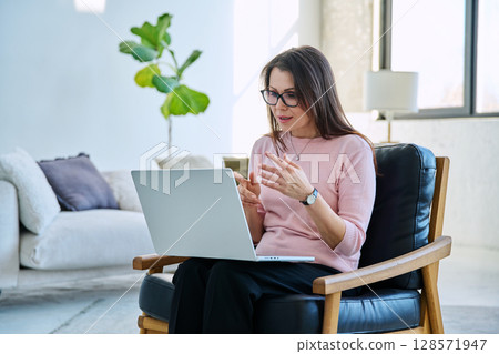 Middle aged woman working remotely, video conference, using laptop 128571947