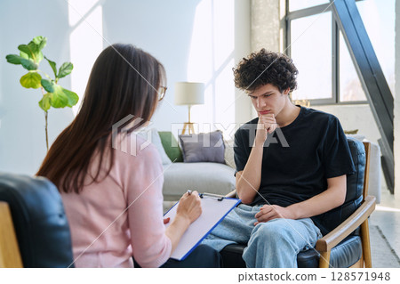 Sad young male patient in therapy session in psychologist counselor office 128571948