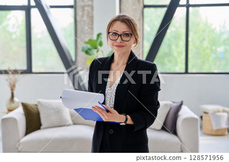 Portrait of woman mentor teacher counselor with clipboard in office looking at camera 128571956